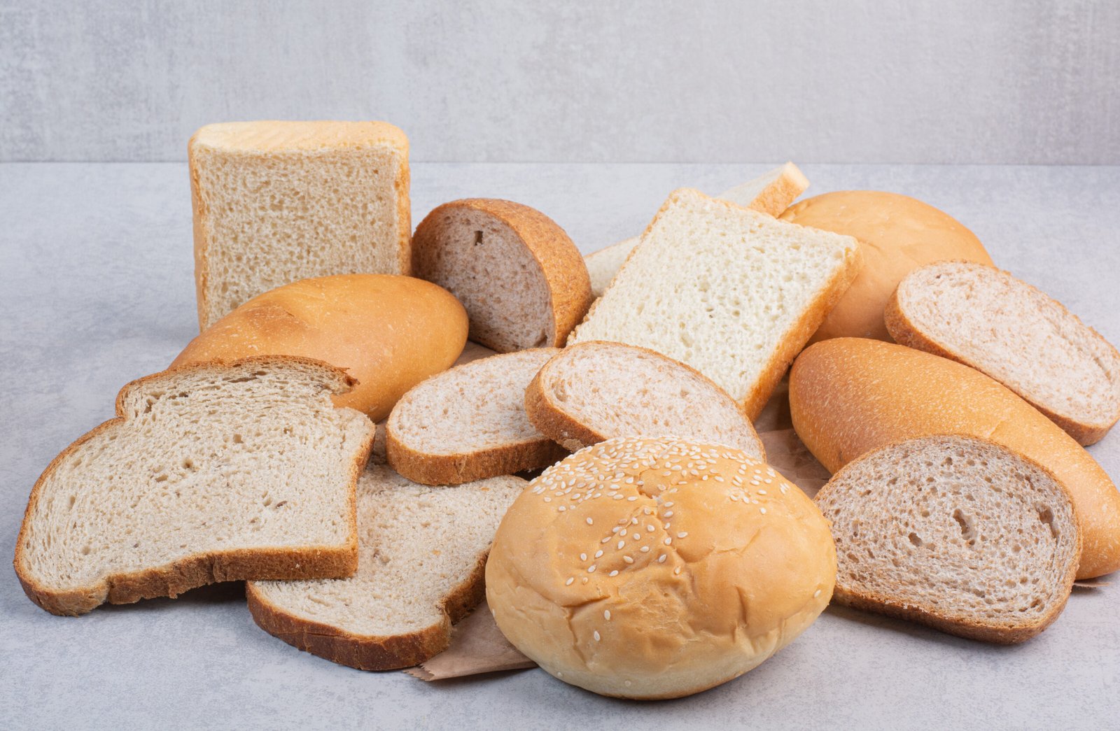 Bread slices and bun with sesame seeds on paper sheet. High quality photo